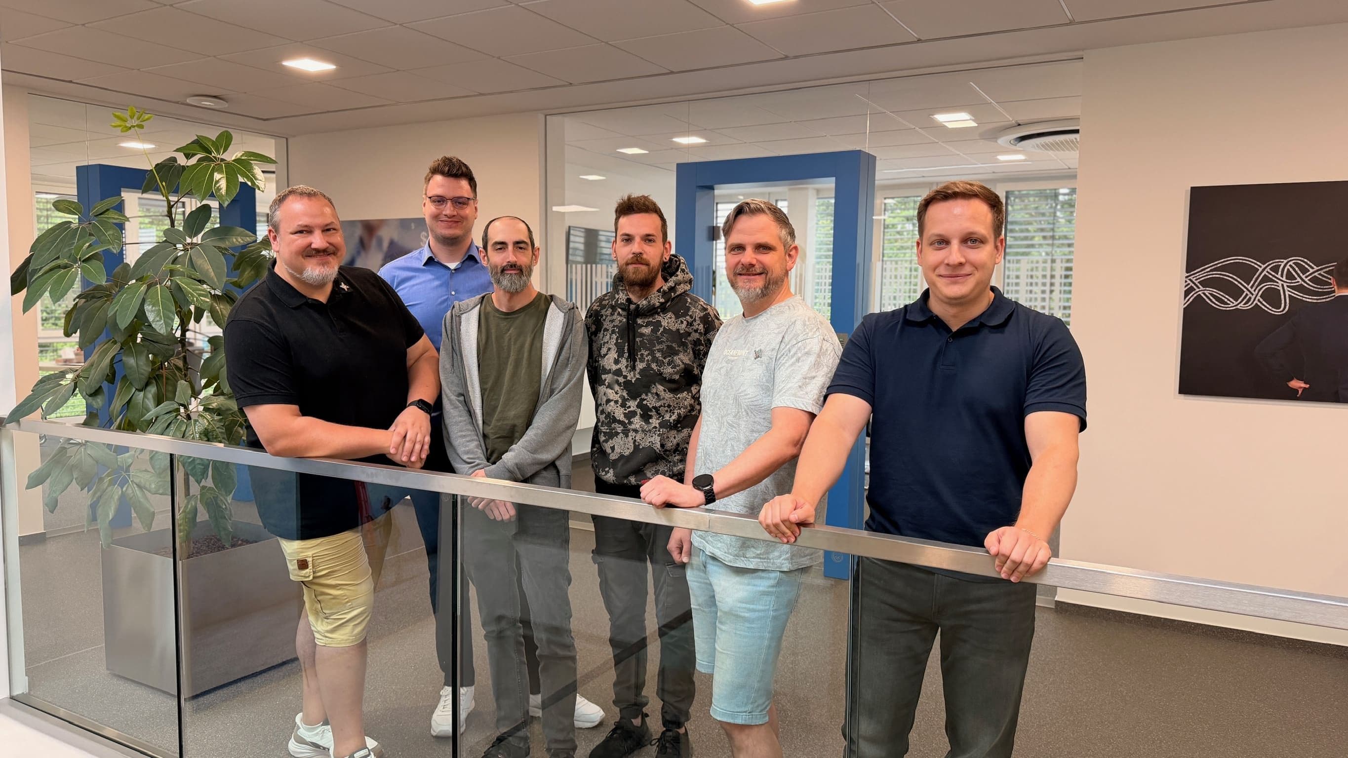 Die Mitarbeiter der IT der Team-IT stehen nebeneinander am Geländer