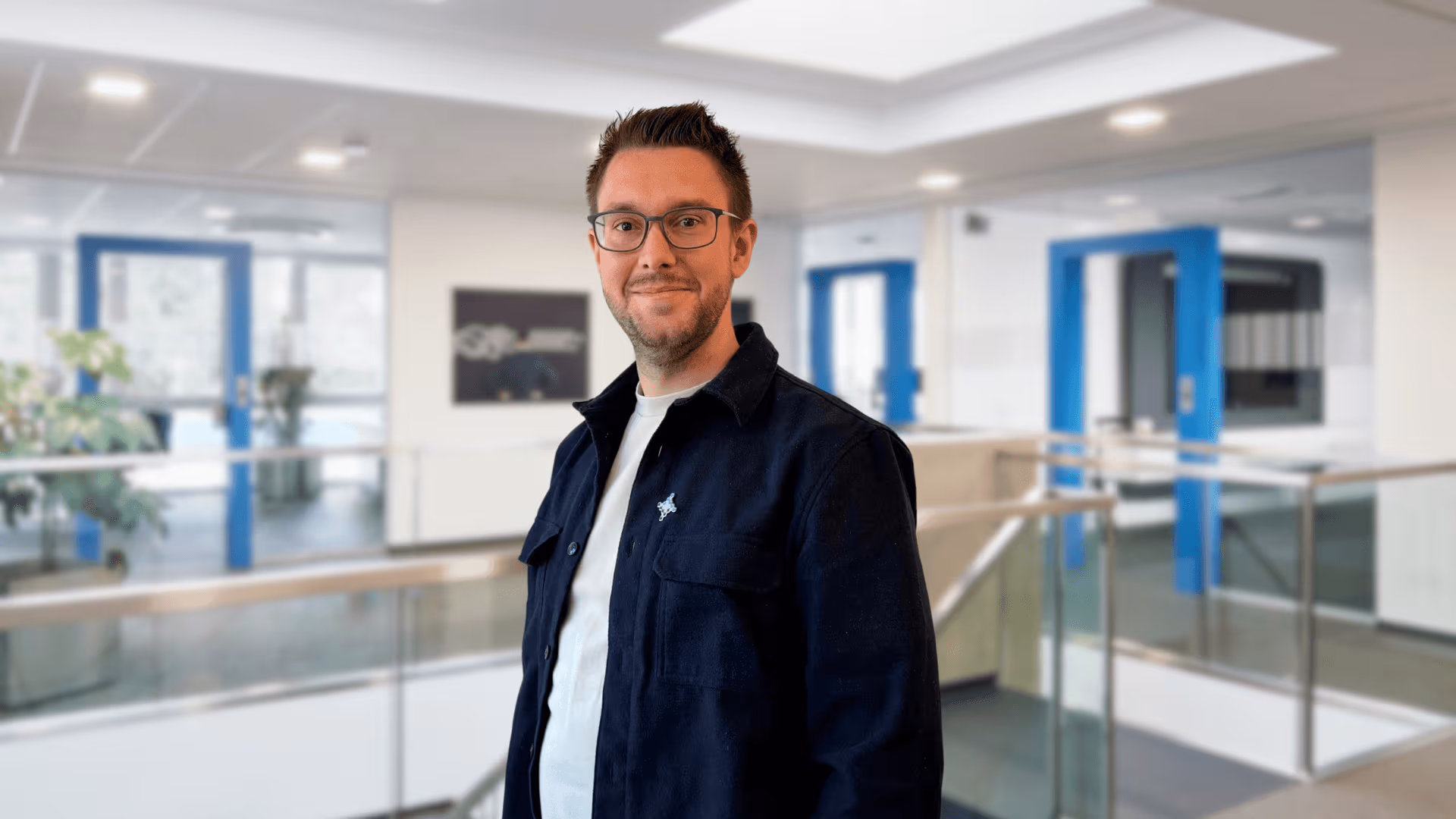 Ein Mitarbeiter der Team-IT Group steht vor einem Geländer in der Firma.