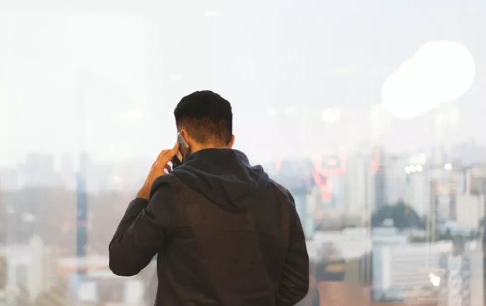 Ein Mann in Rückenansicht der mit Call Routing am Smartphone telefoniert