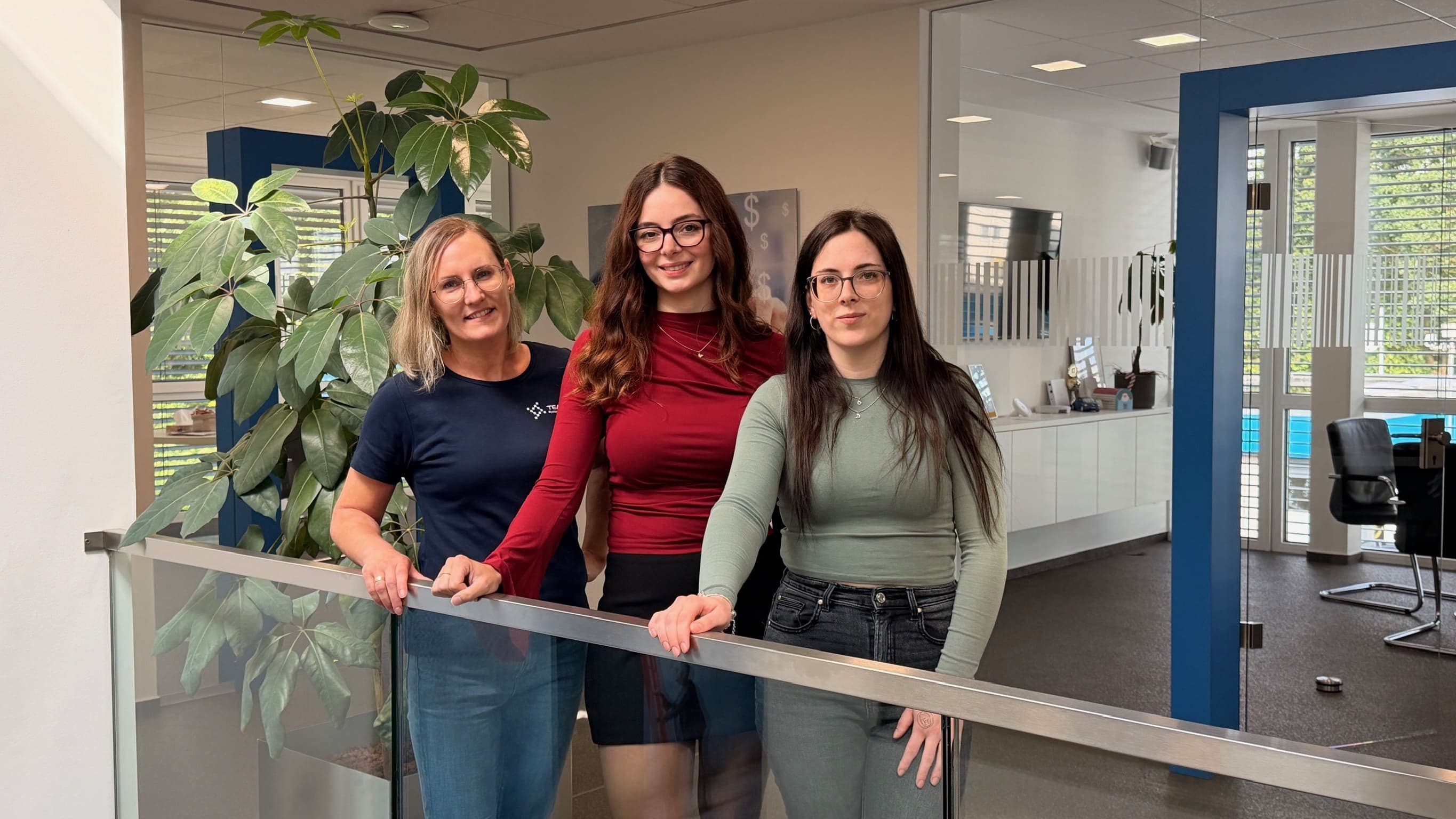 Drei Mitarbeiterinnen der Team-IT stehen zusammen einer Treppe im Frirmengebäude
