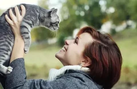 Eine Frau hält eine Katze hoch in die Luft