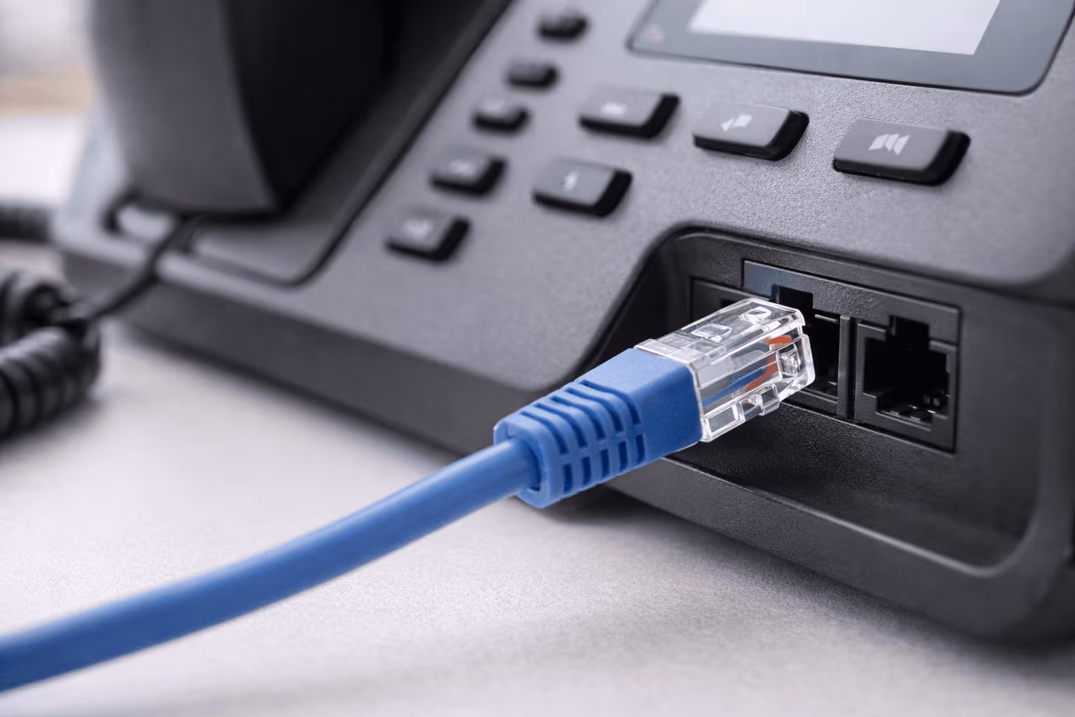 Ein Telefon auf einem Tisch ist mit einem LAN Kabel am Internet angeschlossen