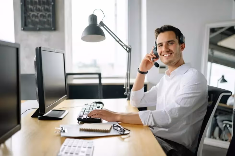 Ein Mann sitzt am Schreibtisch und telefoniert mit Rufnummernmanagement